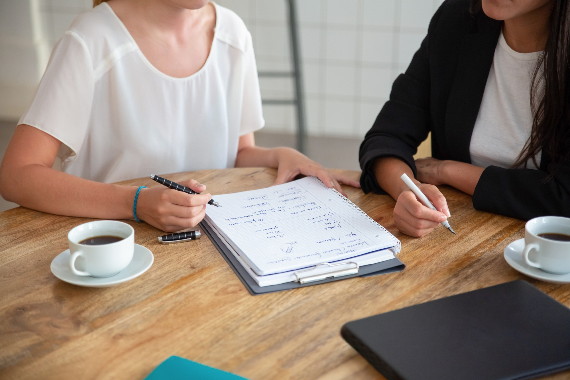 Young-female-colleagues-meeting-discussing-business-plan-writing-strategy-scheme-paper-making-draft