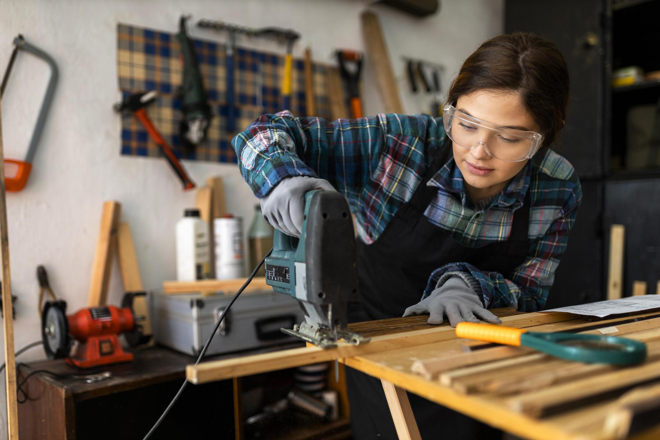 Frau-arbeitet-in-der-werkstatt-mit-bohrhammer